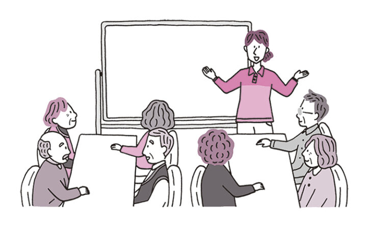 女性の介護者が高齢者(施設利用者)の前でレクリエーションの説明をしている。はっきりとした線で描かれたシンプルなイラスト